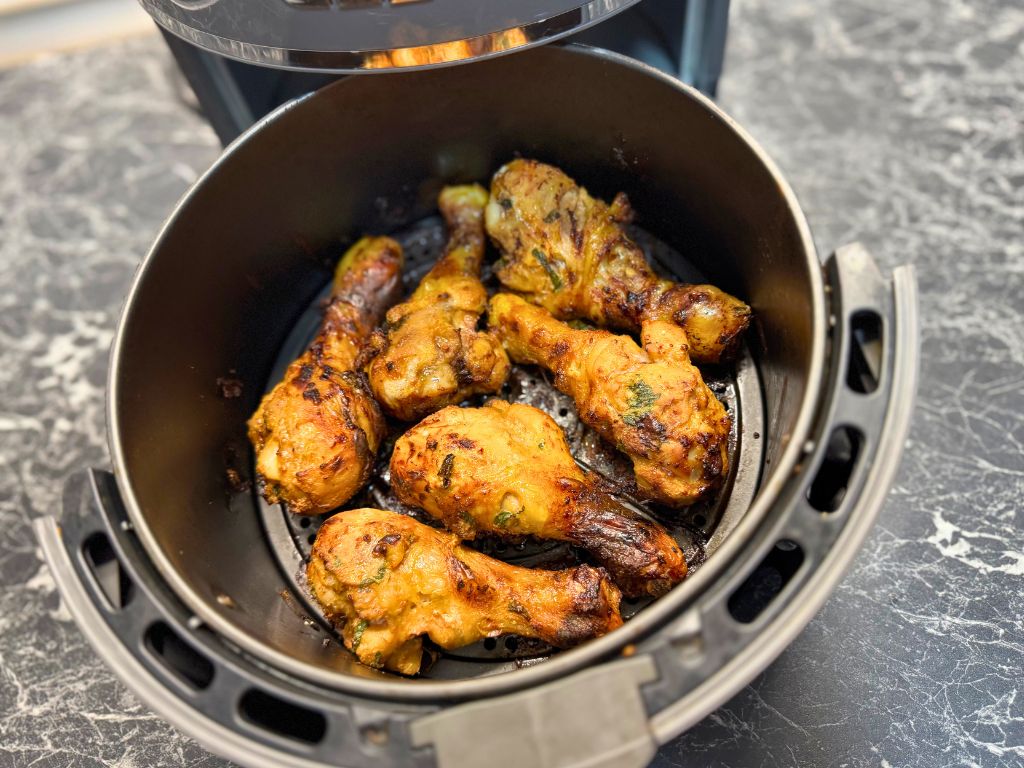 Fully cooked mint-marinated chicken drumsticks with a crispy golden finish inside an open air fryer basket, ready to be served