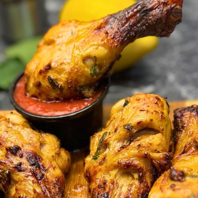 rispy air fryer chicken drumsticks with a mint marinade, served with a red dipping sauce on a wooden board