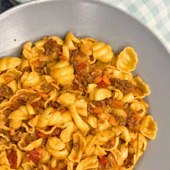 Tuscan Beef Ragu pasta with ground beef, carrots, and tomato sauce on a gray plate.