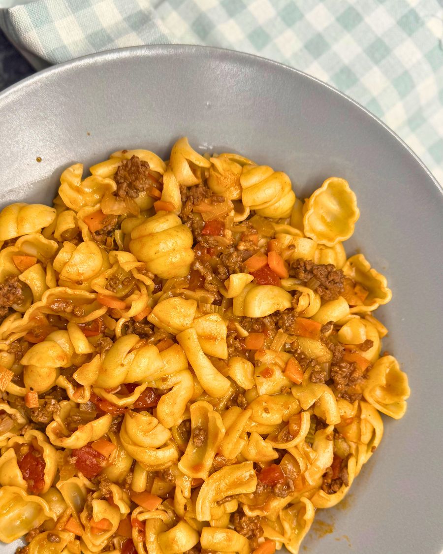 Tuscan Beef Ragu pasta with ground beef, carrots, and tomato sauce on a gray plate.