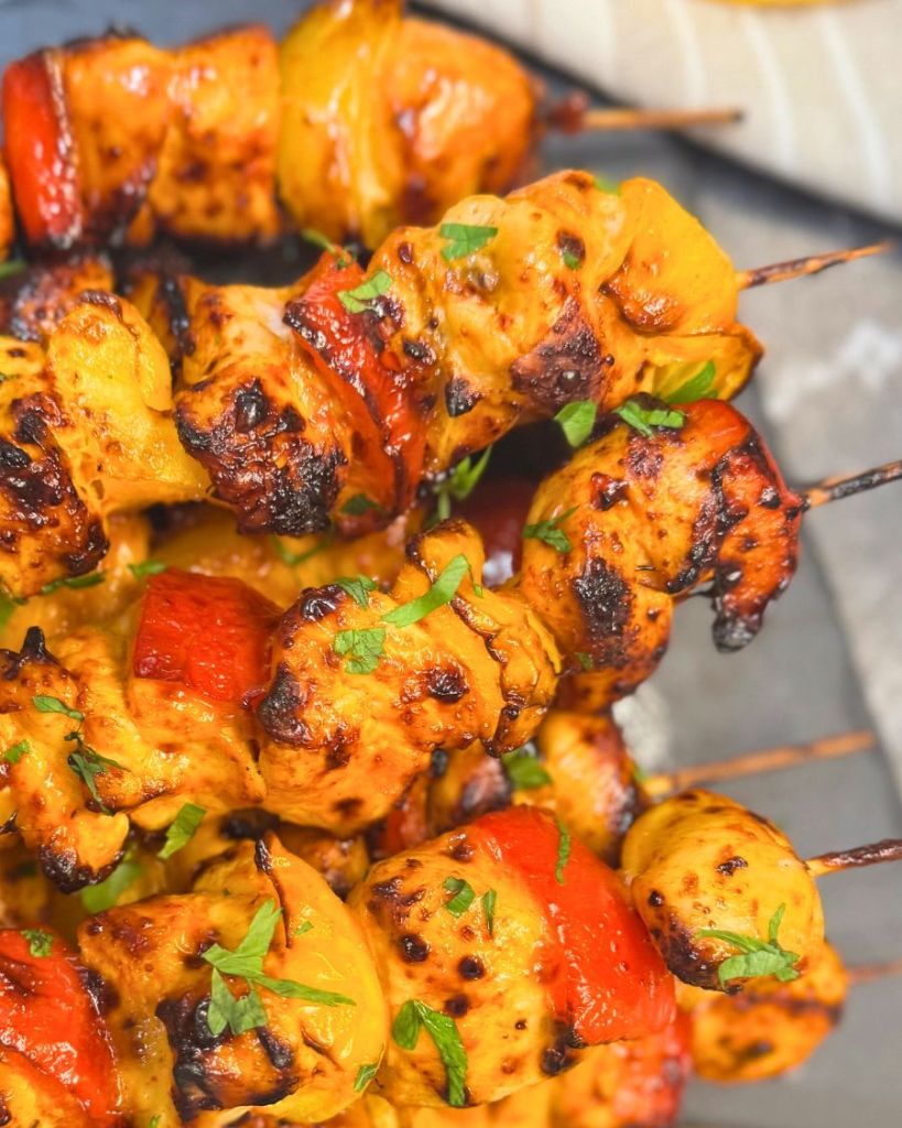 Close-up of juicy air fryer chicken kebabs with red and yellow bell peppers, garnished with fresh parsley.