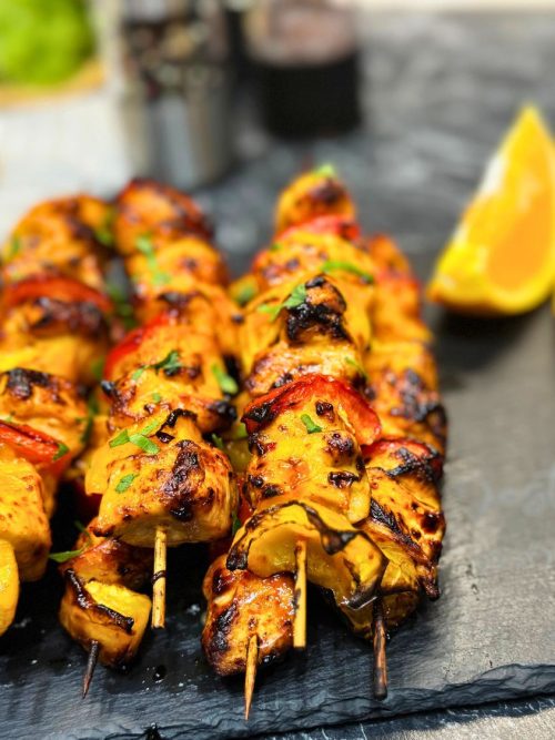 Juicy air fryer chicken kebabs with orange marinade, grilled bell peppers, and fresh parsley on skewers.