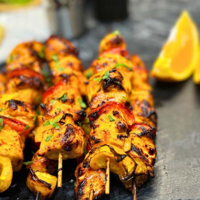 Juicy air fryer chicken kebabs with orange marinade, grilled bell peppers, and fresh parsley on skewers.
