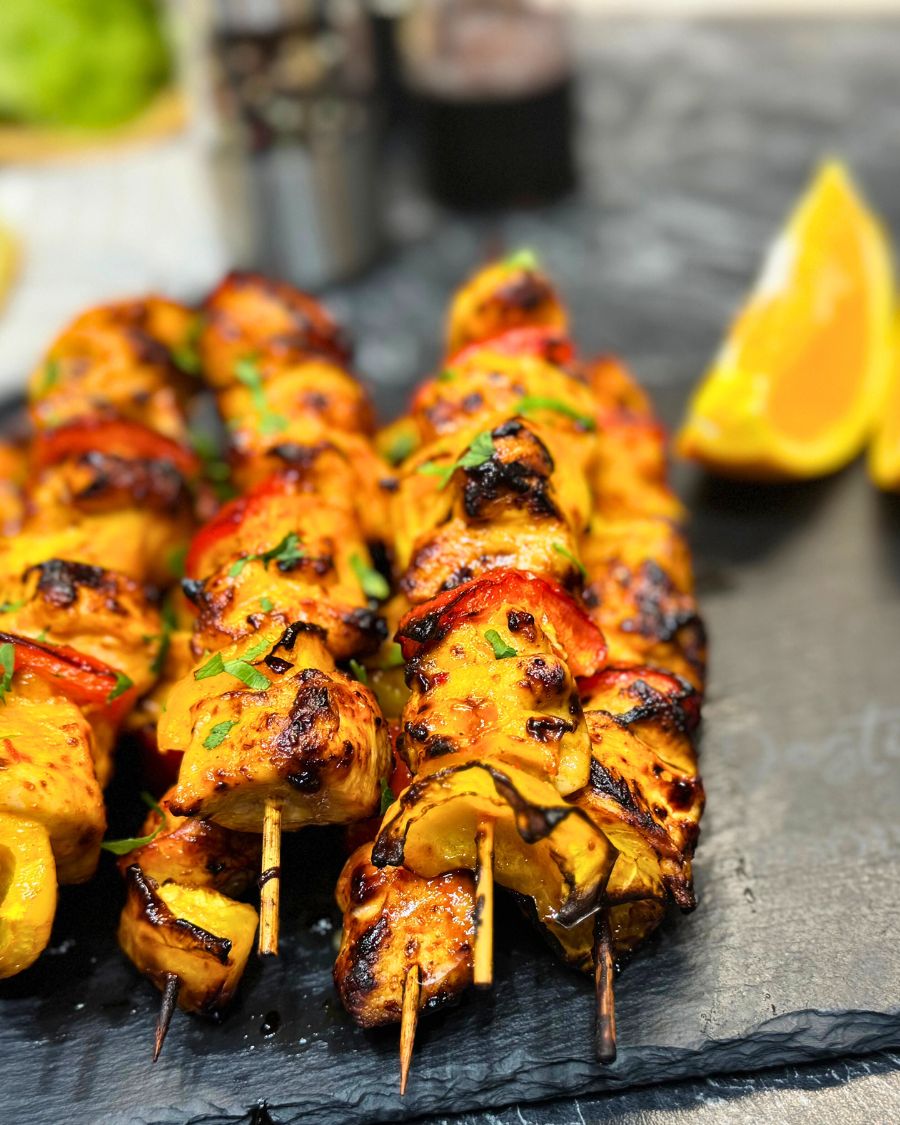 Juicy air fryer chicken kebabs with orange marinade, grilled bell peppers, and fresh parsley on skewers.