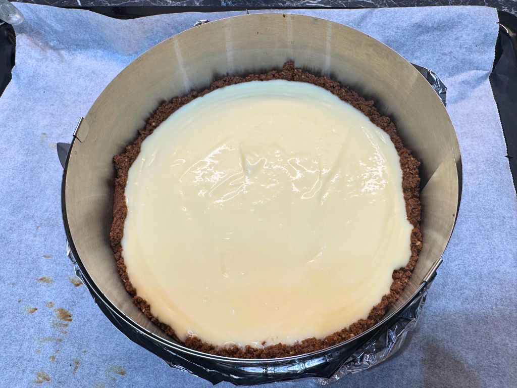 Unbaked peanut butter cheesecake filling poured into a chocolate cookie crust in a springform pan, ready to go into the oven.