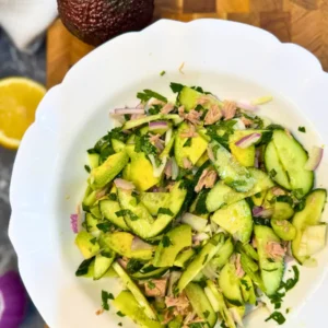 Overhead view of a refreshing tuna cucumber avocado salad in a white bowl.