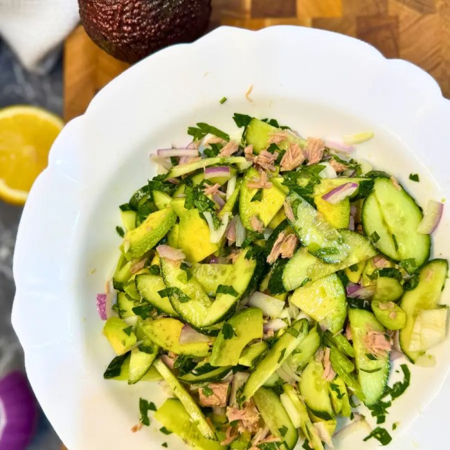 Overhead view of a refreshing tuna cucumber avocado salad in a white bowl.