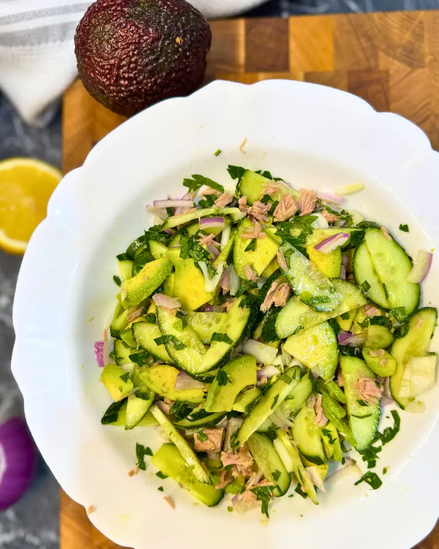 Overhead view of a refreshing tuna cucumber avocado salad in a white bowl.