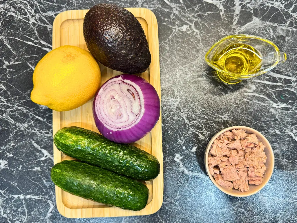 Fresh ingredients for tuna cucumber avocado salad – cucumber, avocado, red onion, lemon, olive oil, and canned tuna.