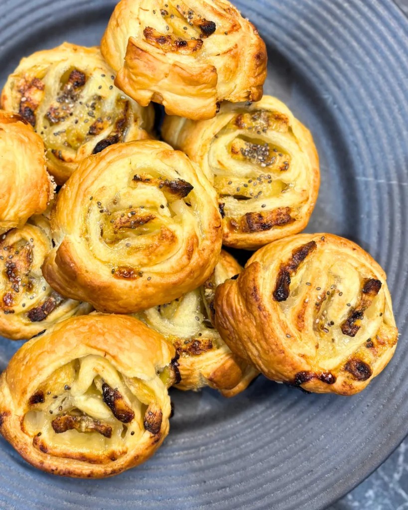 Golden brown banana puff pastry rolls on a plate, topped with chia seeds
