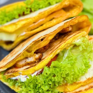 Close-up of homemade chicken tortilla wraps with egg, cheese, and fresh lettuce.