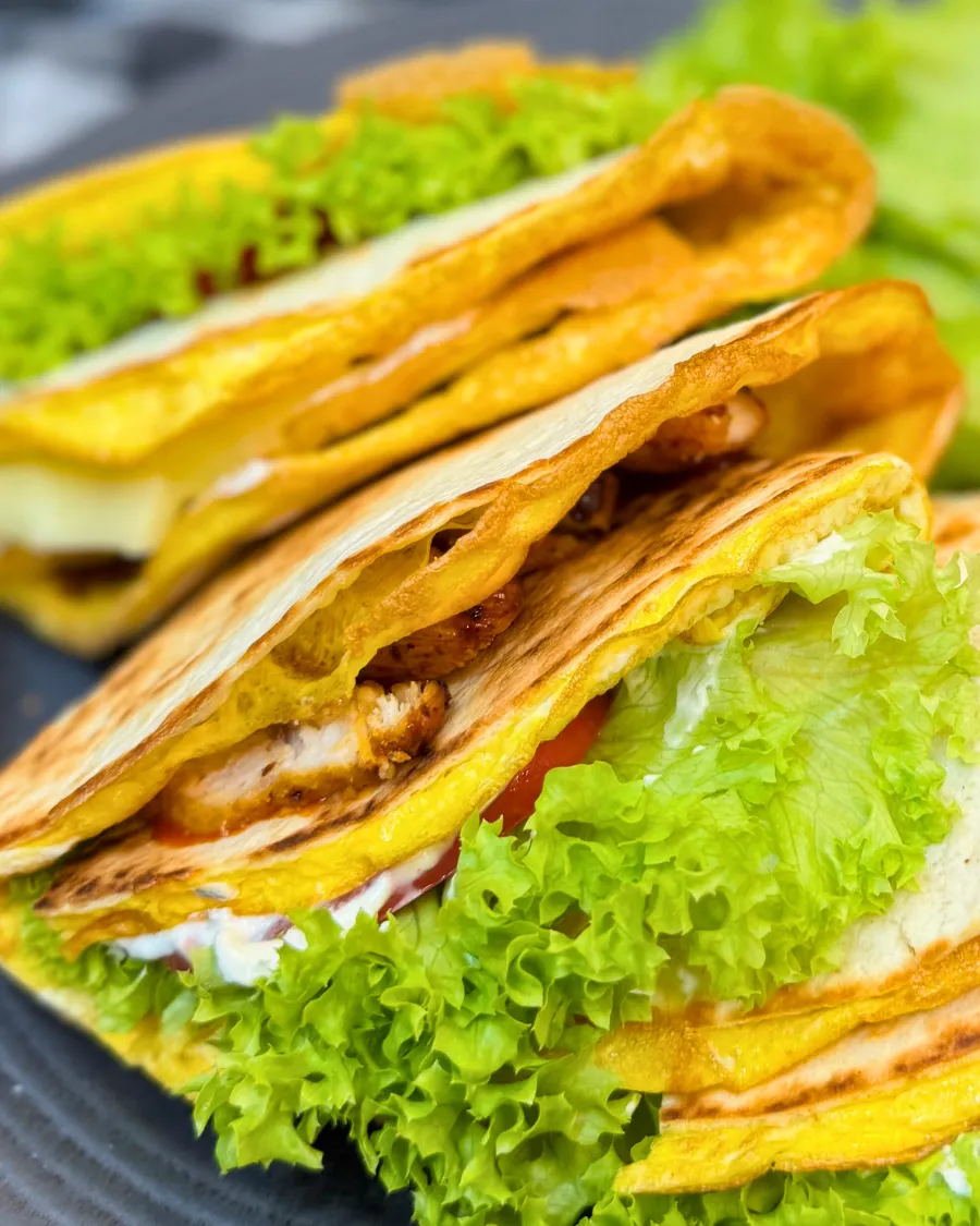 Close-up of homemade chicken tortilla wraps with egg, cheese, and fresh lettuce.