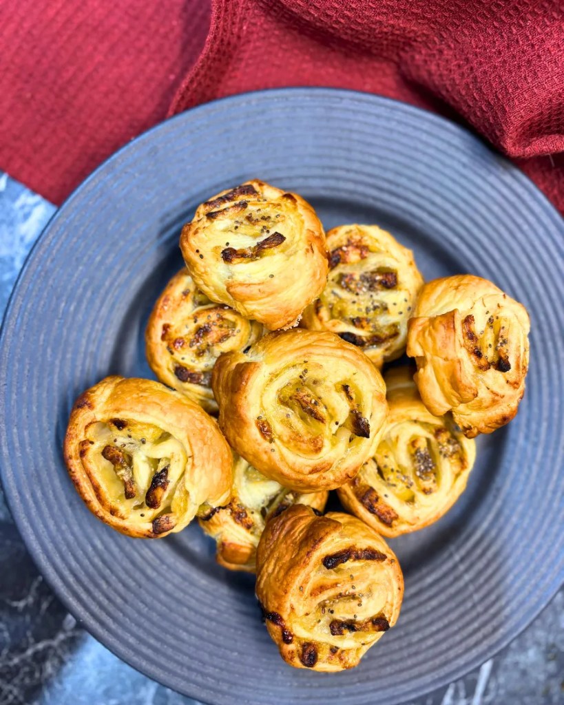 Overhead view of banana puff pastry rolls served on a dark plate with red cloth
