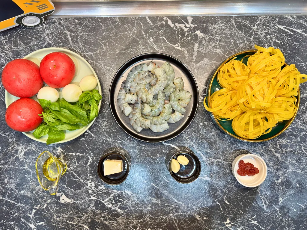 Fresh ingredients for shrimp pasta recipe – tomatoes, basil, pasta, shrimps, garlic, and Parmesan.