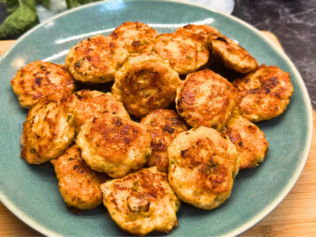 Golden chicken and cheese patties with fresh mint, arranged on a green plate and ready to serve.
