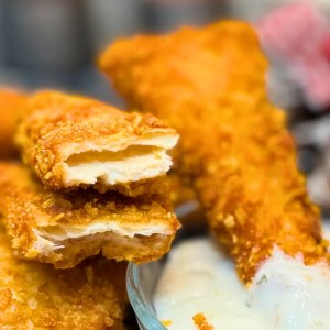 Golden Crispy Chicken Tortilla Bites piled together next to a bowl of dipping sauce.