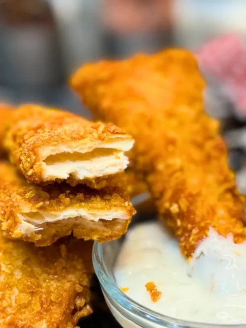 Golden Crispy Chicken Tortilla Bites piled together next to a bowl of dipping sauce.