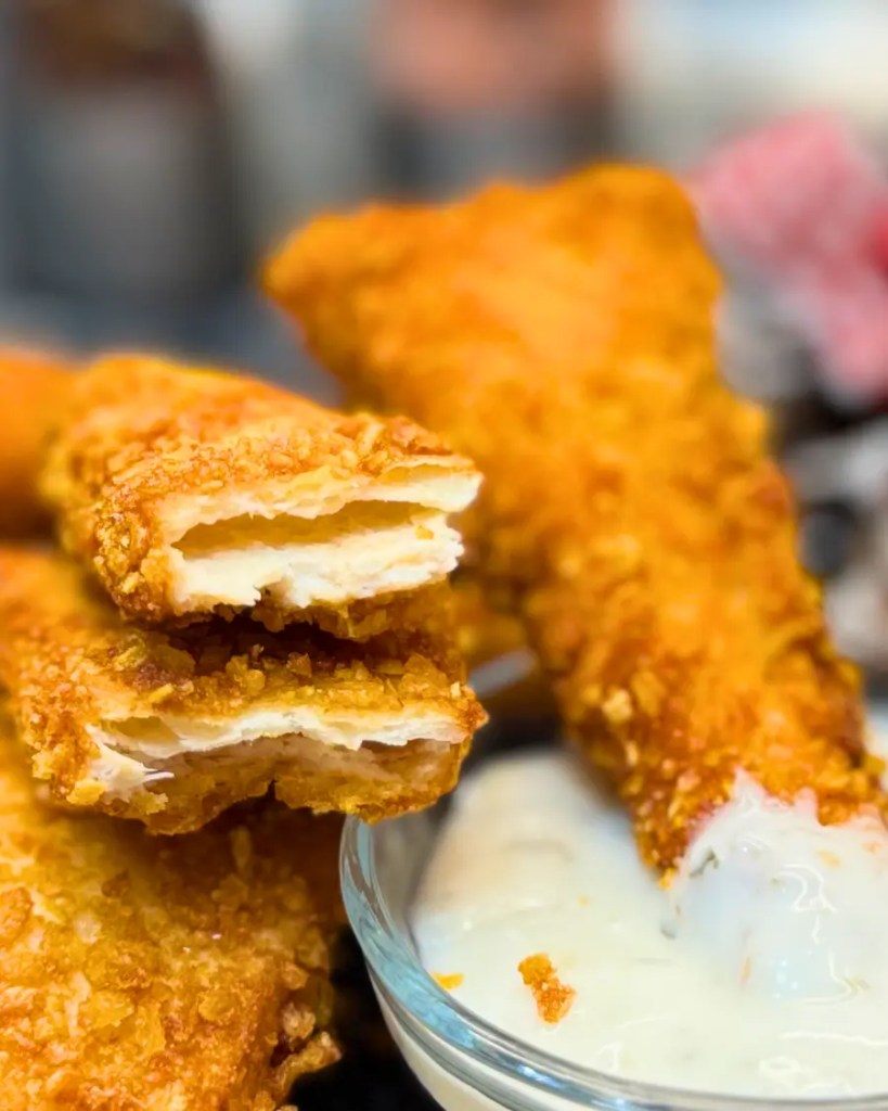 Golden Crispy Chicken Tortilla Bites piled together next to a bowl of dipping sauce.
