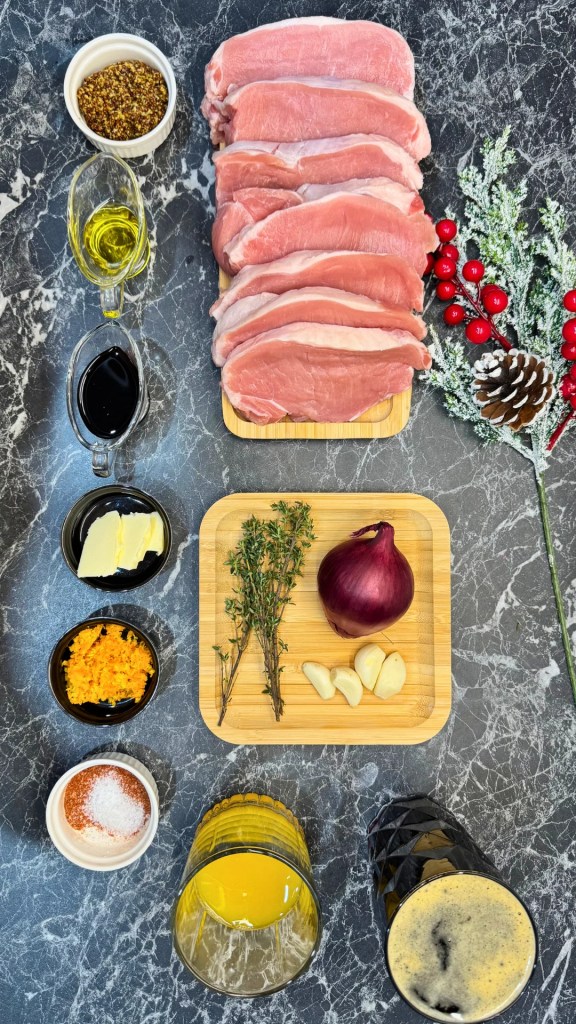 Ingredients for braised pork in dark beer including raw pork slices, dark beer, mustard, orange zest, garlic, red onion, thyme, soy sauce, and spices
