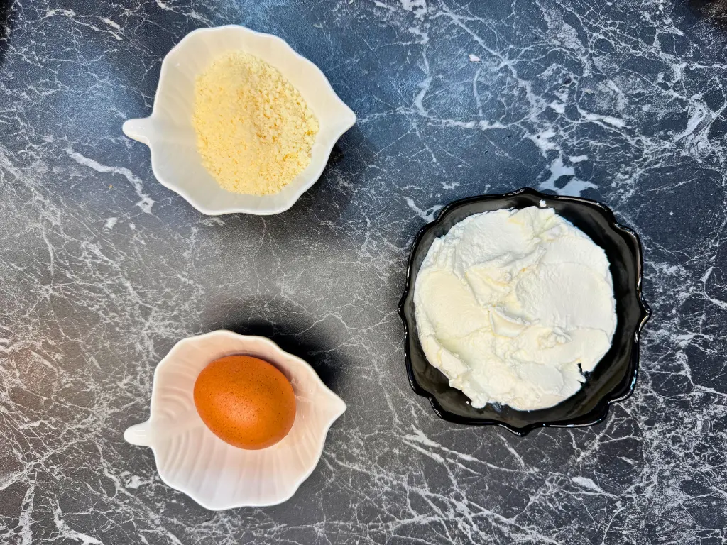Ingredients for the ricotta cheese layer of easy homemade lasagna, including ricotta cheese, grated Parmesan, and an egg