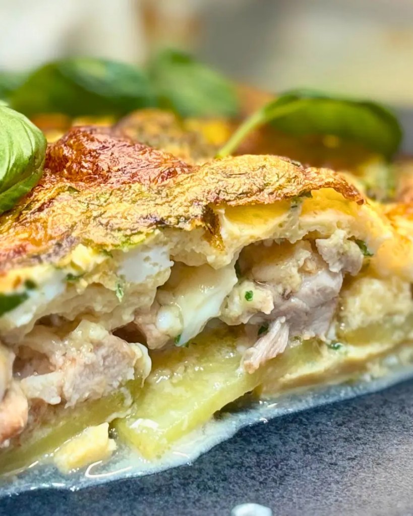Close-up slice of chicken quiche made with potato base, mozzarella balls, eggs, and fresh herbs, showing creamy layers and juicy chicken.