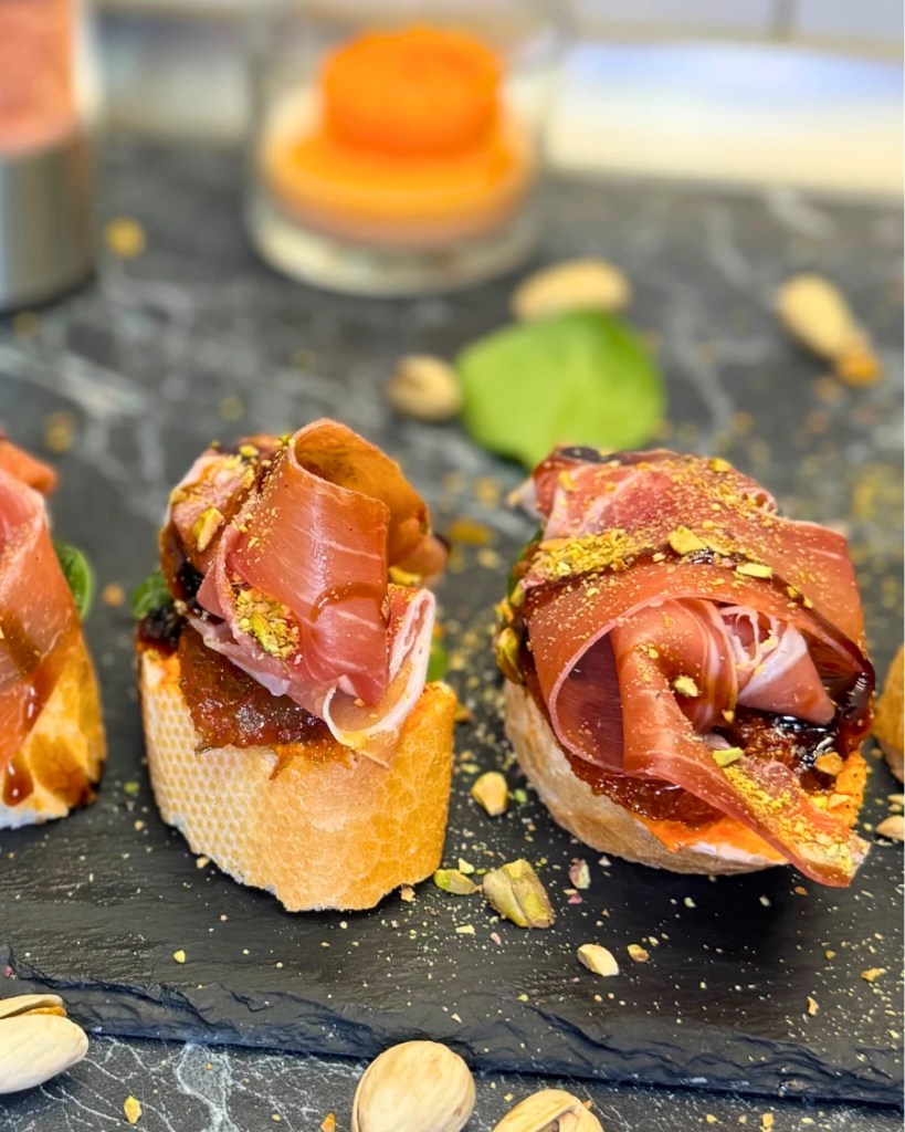 Easy jamon serrano bruschetta appetizer topped with balsamic glaze and pistachios