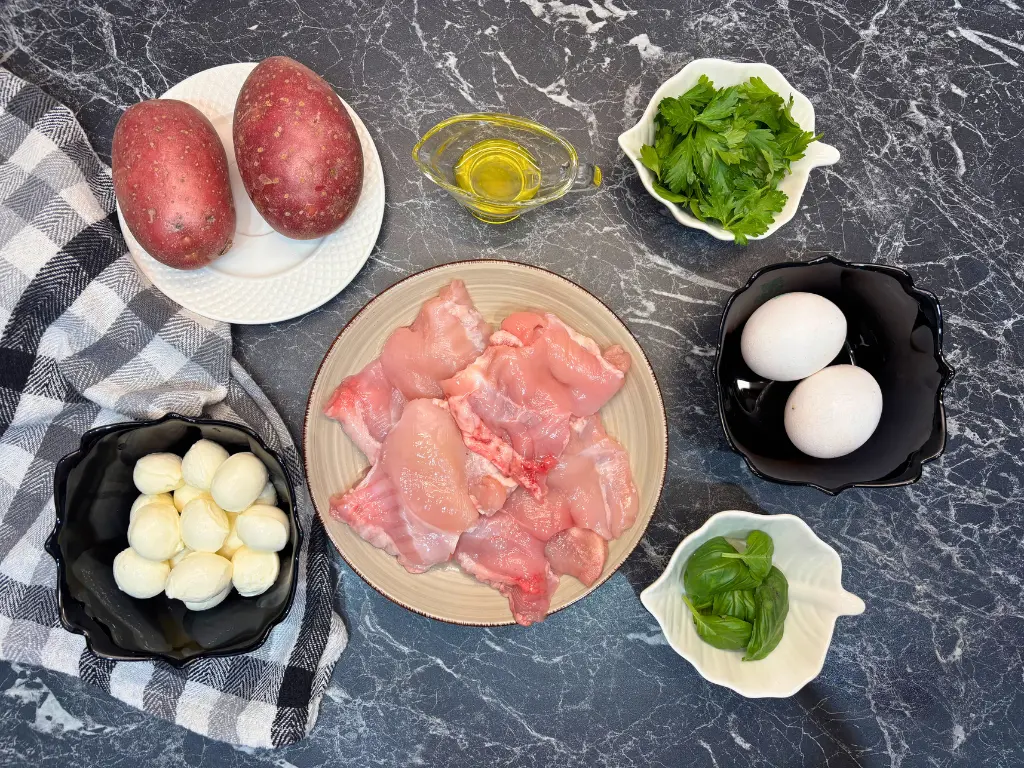 Ingredients for air fryer chicken quiche including potatoes, boneless chicken thighs, mozzarella balls, eggs, olive oil, parsley, and fresh basil.