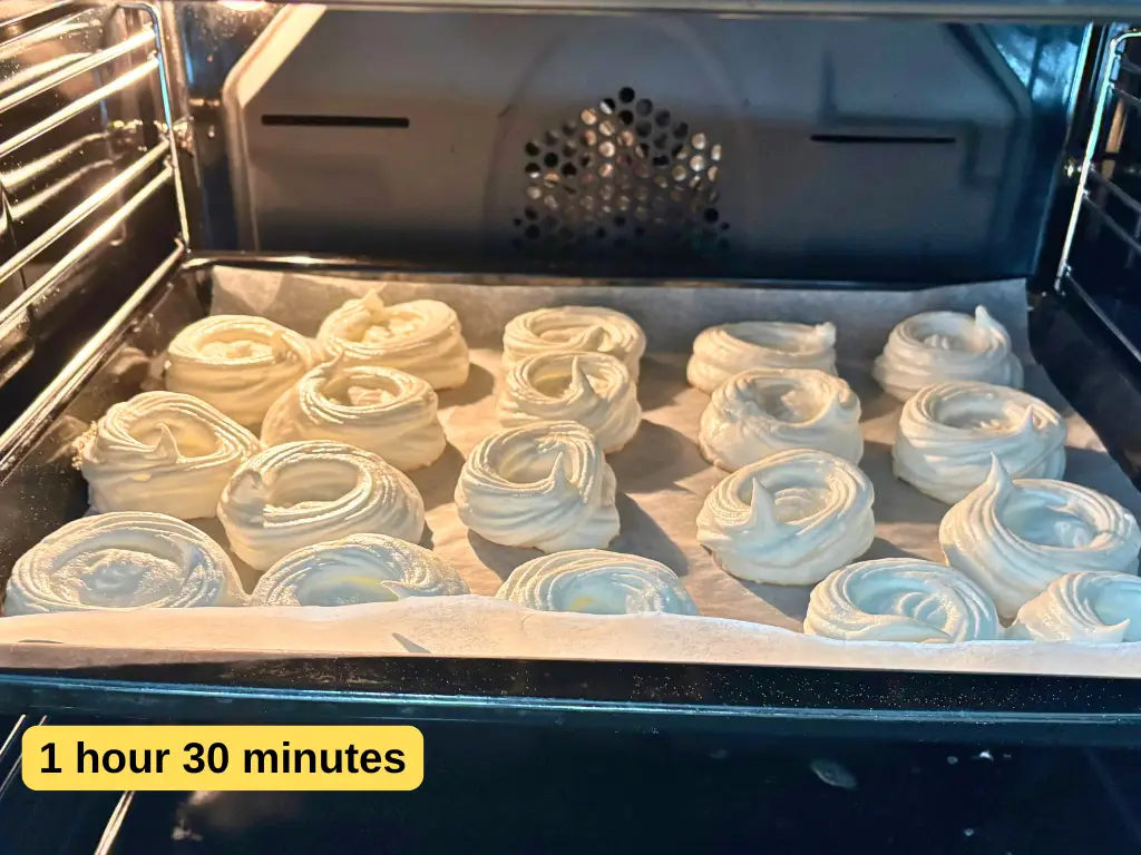 Mini pavlova meringues baking slowly in the oven for a crisp shell and soft center