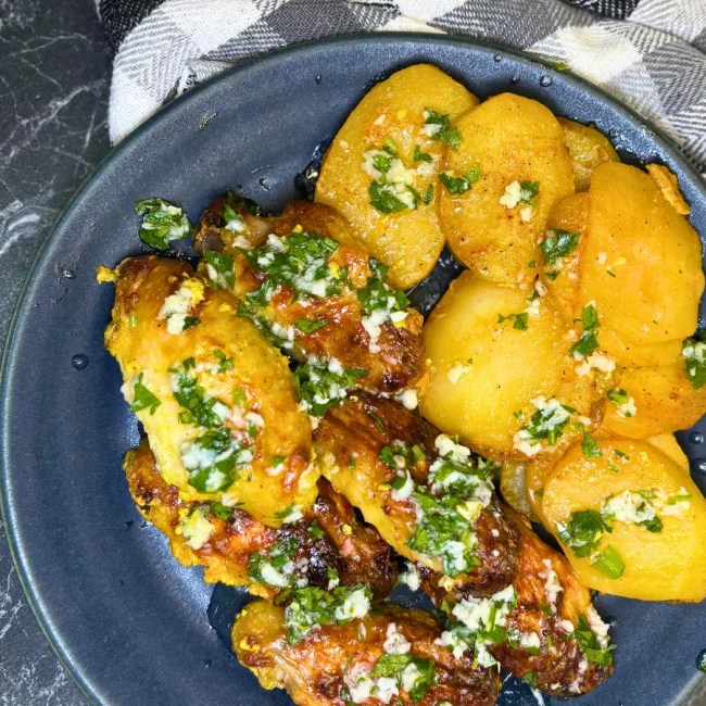 Homemade oven baked lemon garlic chicken wings with tender roasted potatoes and fresh herb garlic sauce