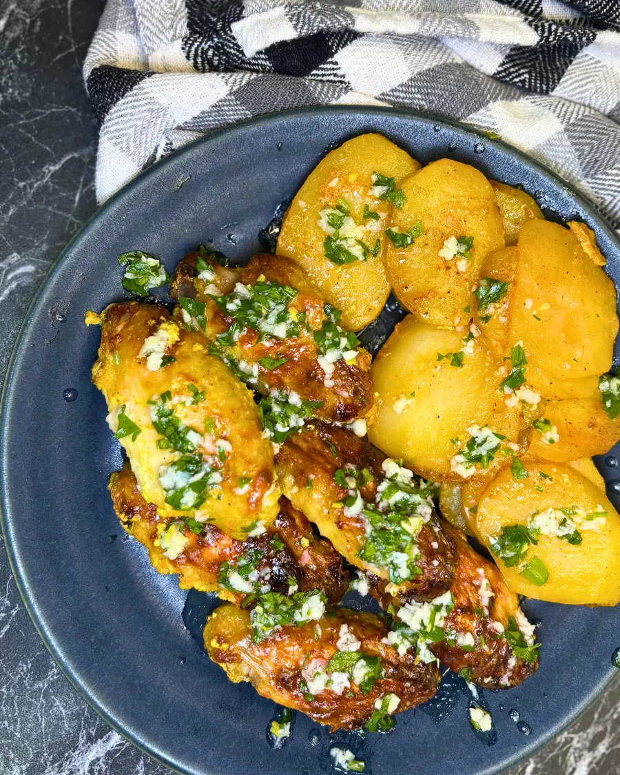 Homemade oven baked lemon garlic chicken wings with tender roasted potatoes and fresh herb garlic sauce