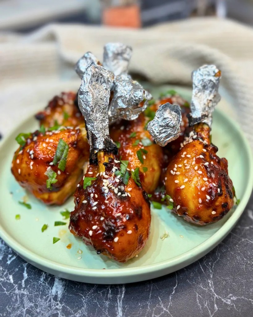 Air fryer chicken drumsticks with sweet chili BBQ glaze and sesame garnish
