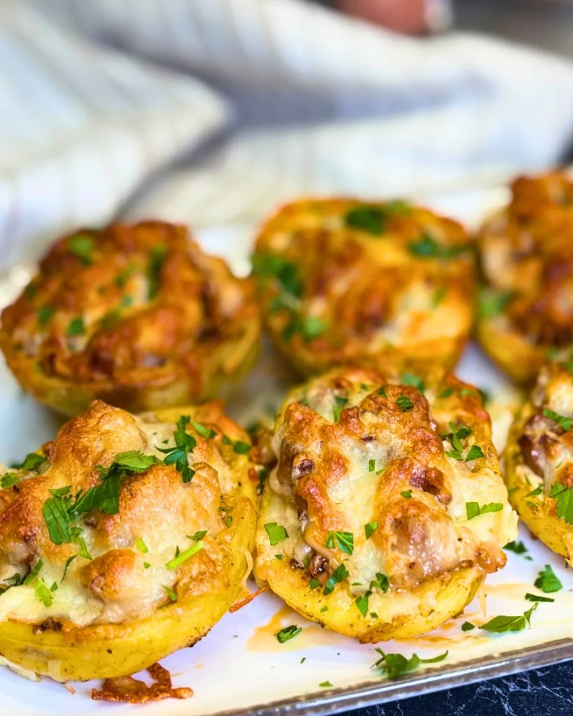 Close-up of crispy baked stuffed potatoes filled with chicken and topped with melted cheese and fresh herbs.