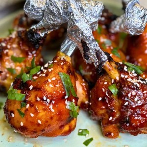 Sticky air fryer chicken drumsticks served with sesame seeds and green onions