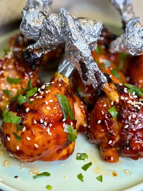 Sticky air fryer chicken drumsticks served with sesame seeds and green onions