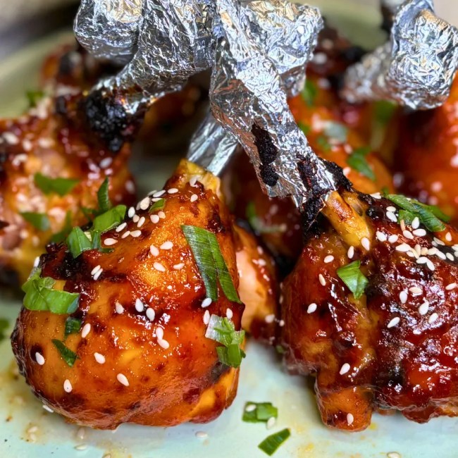 Sticky air fryer chicken drumsticks served with sesame seeds and green onions
