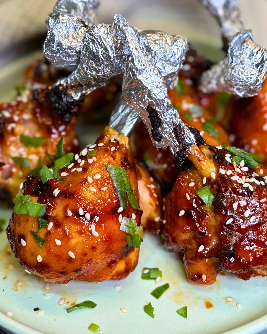 Sticky air fryer chicken drumsticks served with sesame seeds and green onions