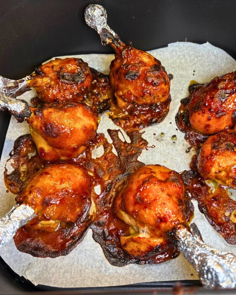 Sticky air fryer chicken drumsticks cooking with caramelized BBQ teriyaki glaze