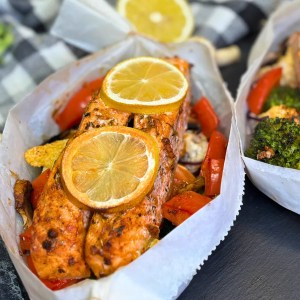 salmon and vegetables in parchment paper baked in the oven with lemon slices