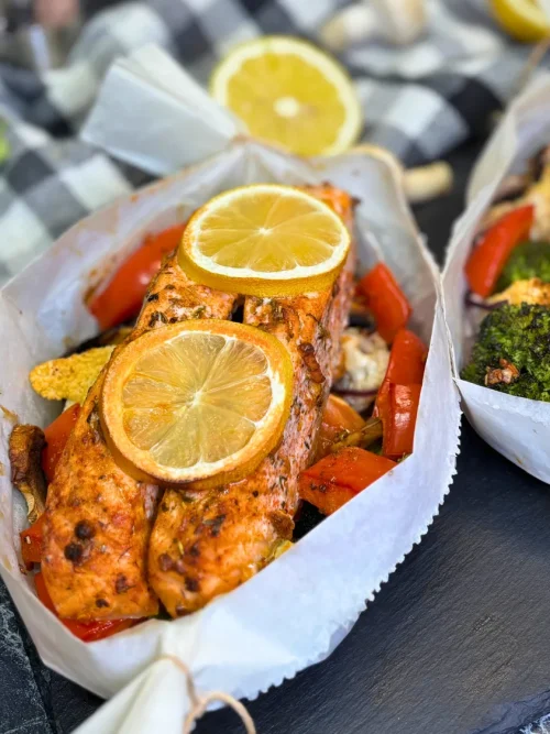 salmon and vegetables in parchment paper baked in the oven with lemon slices