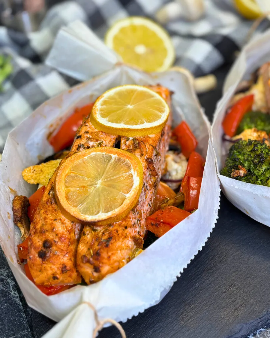 salmon and vegetables in parchment paper baked in the oven with lemon slices
