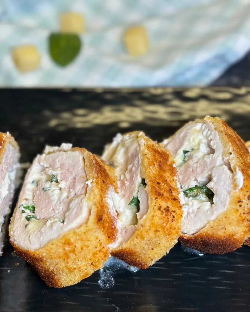 Homemade turkey roulade cut into slices showing creamy spinach cheese filling