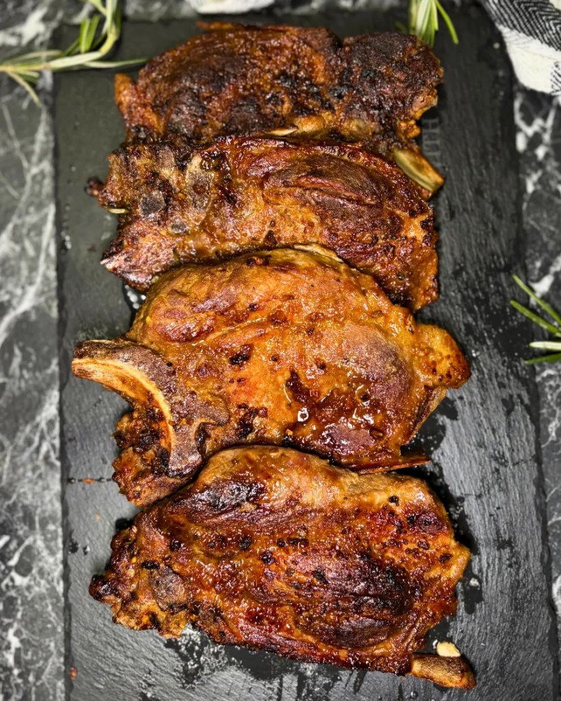 Juicy air fryer pork steaks served on a black plate with garlic and rosemary