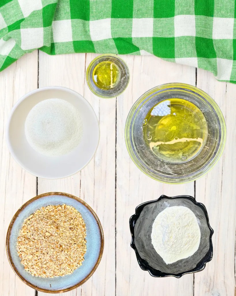 Ingredients for Kyiv cake layers including egg whites, sugar, hazelnuts, and flour arranged on a wooden surface