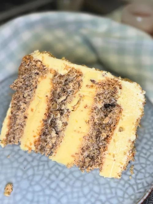 Slice of Kyiv cake with hazelnut meringue layers and creamy butter filling