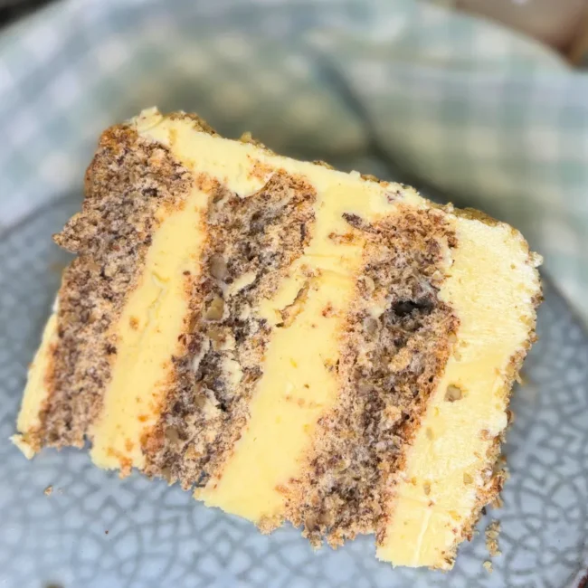Slice of Kyiv cake with hazelnut meringue layers and creamy butter filling