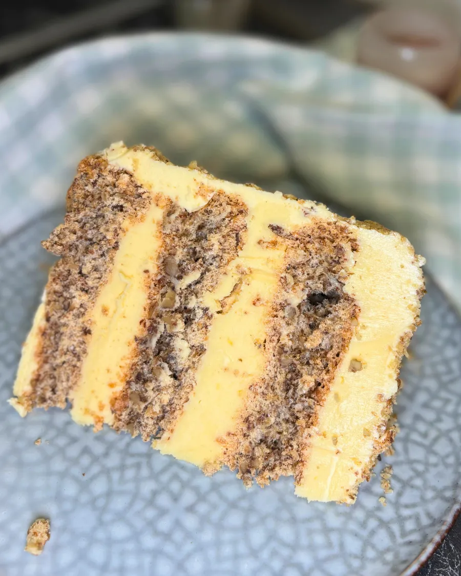 Slice of Kyiv cake with hazelnut meringue layers and creamy butter filling