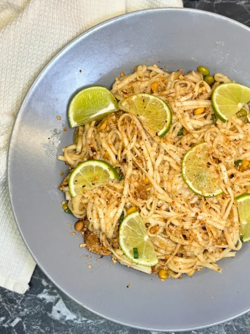 easy chicken ramen noodles served in a bowl with lime, green onions, peanuts, and vegetables