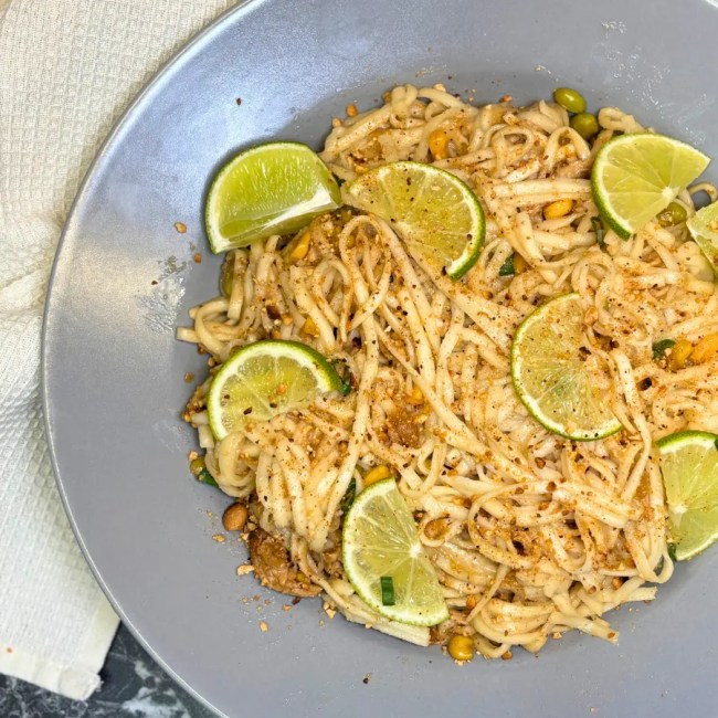 easy chicken ramen noodles served in a bowl with lime, green onions, peanuts, and vegetables