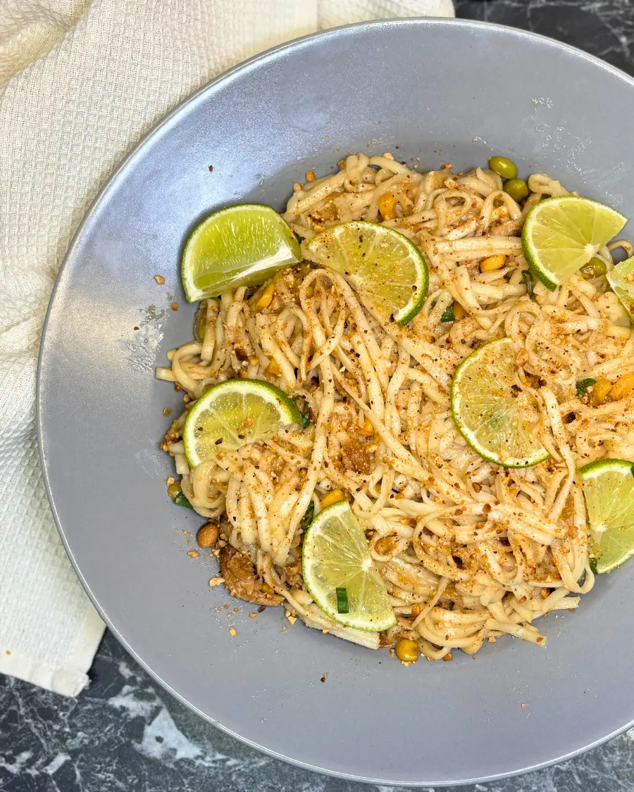 easy chicken ramen noodles served in a bowl with lime, green onions, peanuts, and vegetables