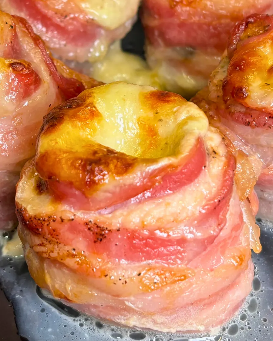 Close up of baked chicken bacon mozzarella roll ups with melted cheese and crispy bacon.